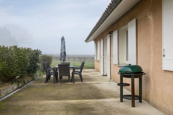 Un patio con mesa y sillas, una parrilla y una sombrilla.