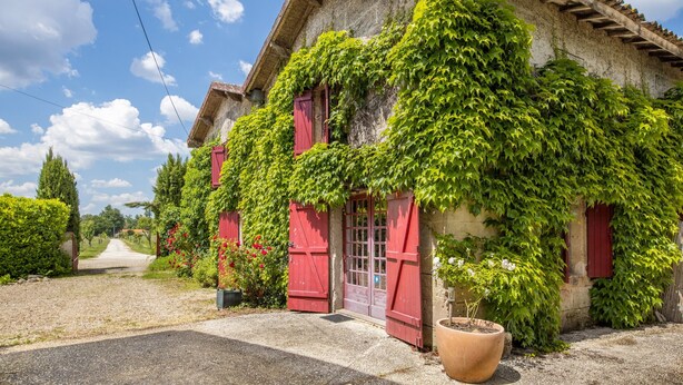 A building with red shutters and a gravel driveway.
