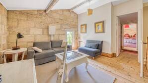 A living room with stone walls, two grey sofas, a white coffee table, and a wooden floor.