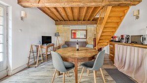A dining area with a wooden table, grey chairs, and a bottle of wine.