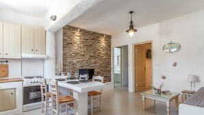 Eine moderne Küche mit Steinwand, weißen Schränken und einem Essbereich mit einem Glastisch.