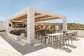 An outdoor patio area with a bar, seating, and a view of the landscape.