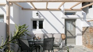 Eine Terrasse im Freien mit Tisch und Stühlen, einer Steinmauer und einer Holzpergola.