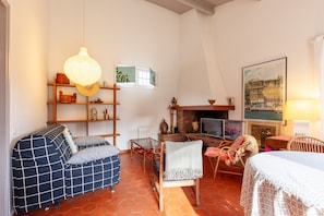 A cozy room with a sofa, a chair, a table, a fireplace, and a bookshelf. - Holiday Home 'Lou Jas - Cassis' with Private Terrace and Wi-Fi (Cassis)