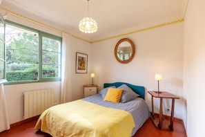 A bedroom with a bed, bedside lamps, a window, a radiator, and a mirror on the wall. - Holiday Home 'Lou Jas - Cassis' with Private Terrace and Wi-Fi (Cassis)