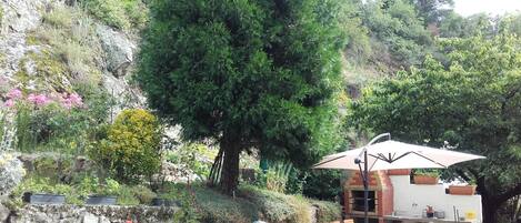 Un patio con una mesa, sillas, un horno de ladrillo y un muro de piedra.