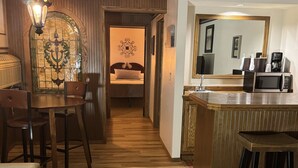 A hotel room with a dining area, a kitchenette, and a bed. - Fenway House Hotel (Fennimore)