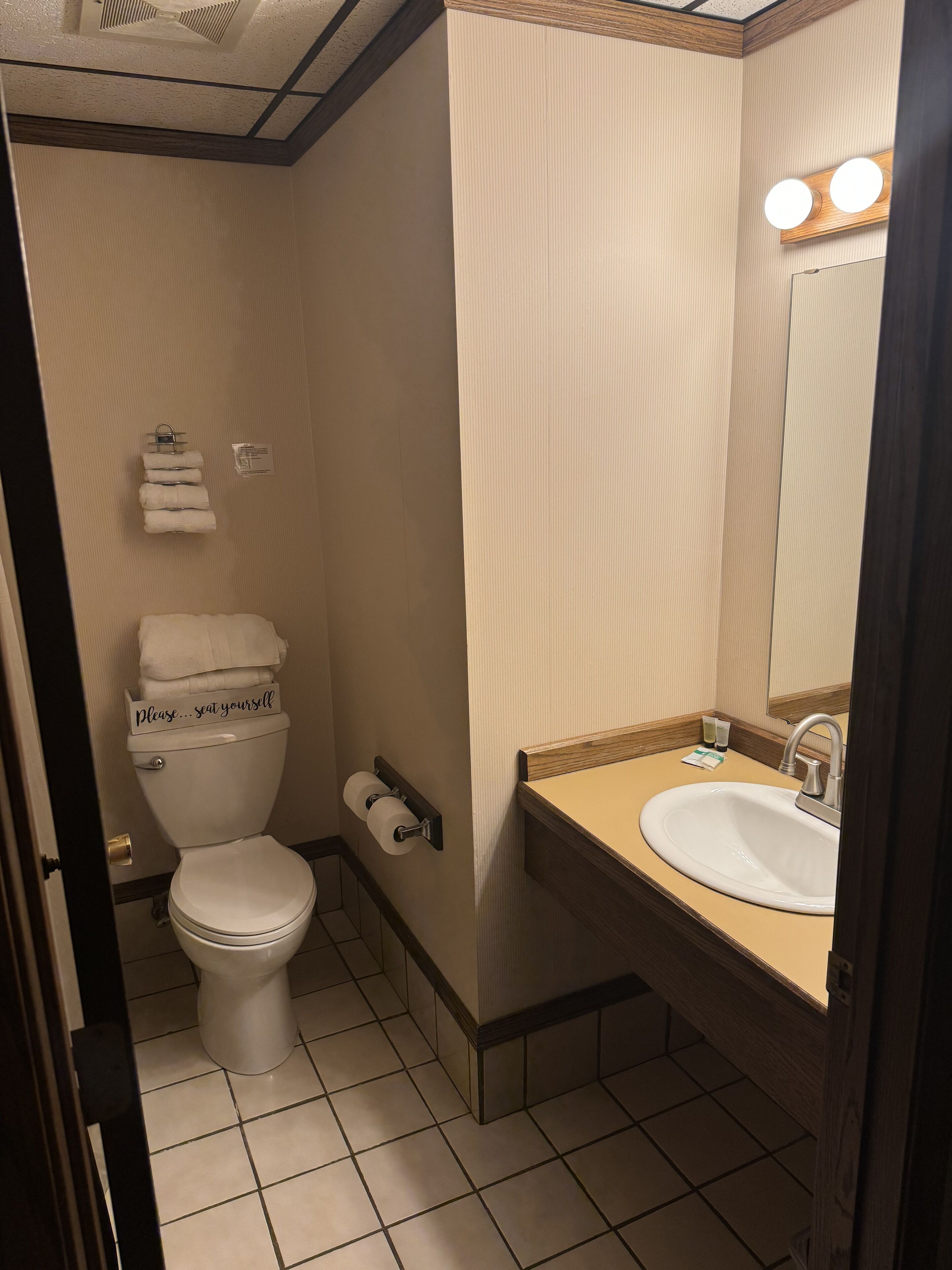 A compact bathroom with a toilet, sink, and mirror.