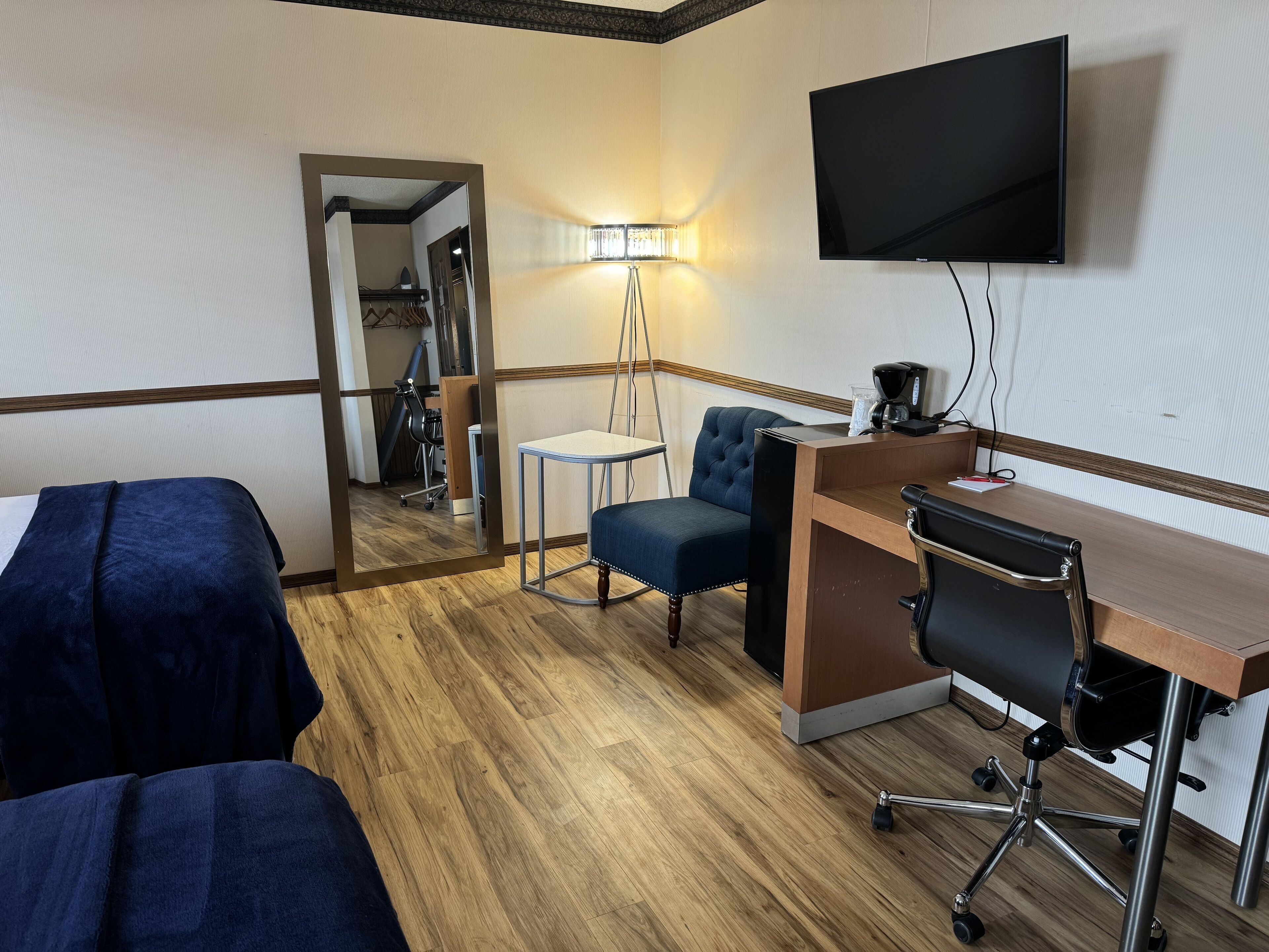 Ett hotellrum med två sängar, ett skrivbord med en stol, en tv och en lampa.