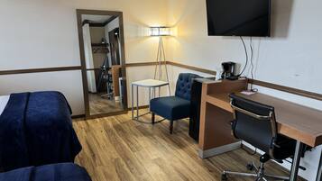 Ett hotellrum med två sängar, ett skrivbord med en stol, en tv och en lampa.