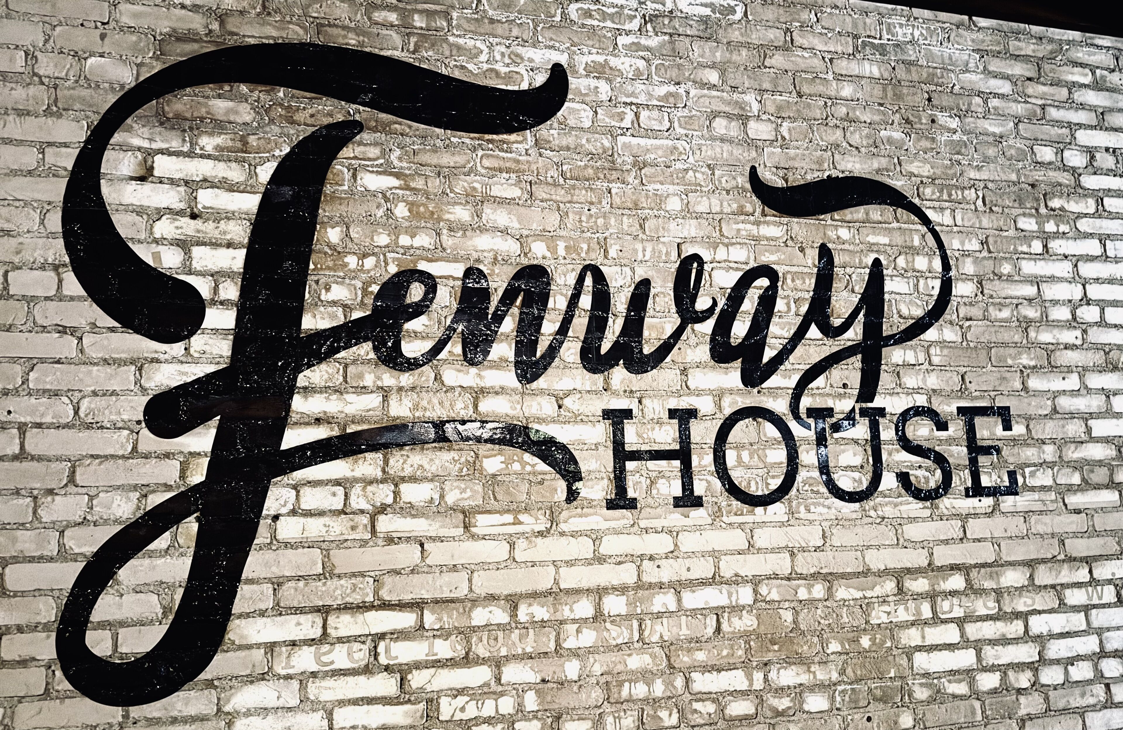 A brick wall with the words "Fennway HOUSE" in large, stylized lettering.