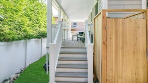 A covered outdoor staircase leading to a deck area with a wooden fence and a white railing.