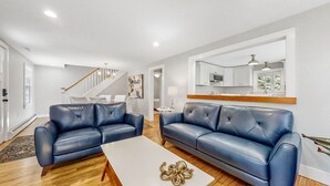A modern living room with two blue leather sofas, a white coffee table, and a wooden floor.