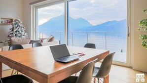 Una habitación moderna con una mesa de comedor de madera, una computadora portátil y un árbol de Navidad.