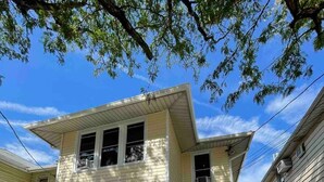 A two-story house with a front porch, a small front yard, and a visible garage.