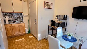 A compact kitchen with wooden cabinets, a microwave, and a coffee maker on a small table.