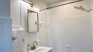 Un bagno con lavandino bianco, rubinetteria dorata e tenda da doccia.