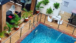 A swimming pool with a metal safety railing, surrounded by potted plants and outdoor furniture. - Willowwood Hotel Owerri (Owerri)