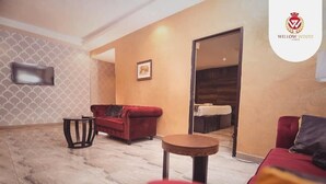 A modern living room with a red sofa, a small round table, and a television mounted on the wall. - Willowwood Hotel Owerri (Owerri)