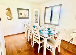 A dining area with a wooden table, white chairs, and blue bowls.