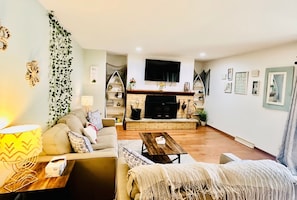 A living room with a sofa, coffee table, and a TV mounted on the wall.