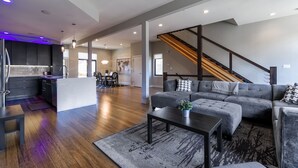 Ein geräumiger Wohnbereich mit grauem Sofa, Couchtisch und einer Treppe zu einer weiteren Ebene.