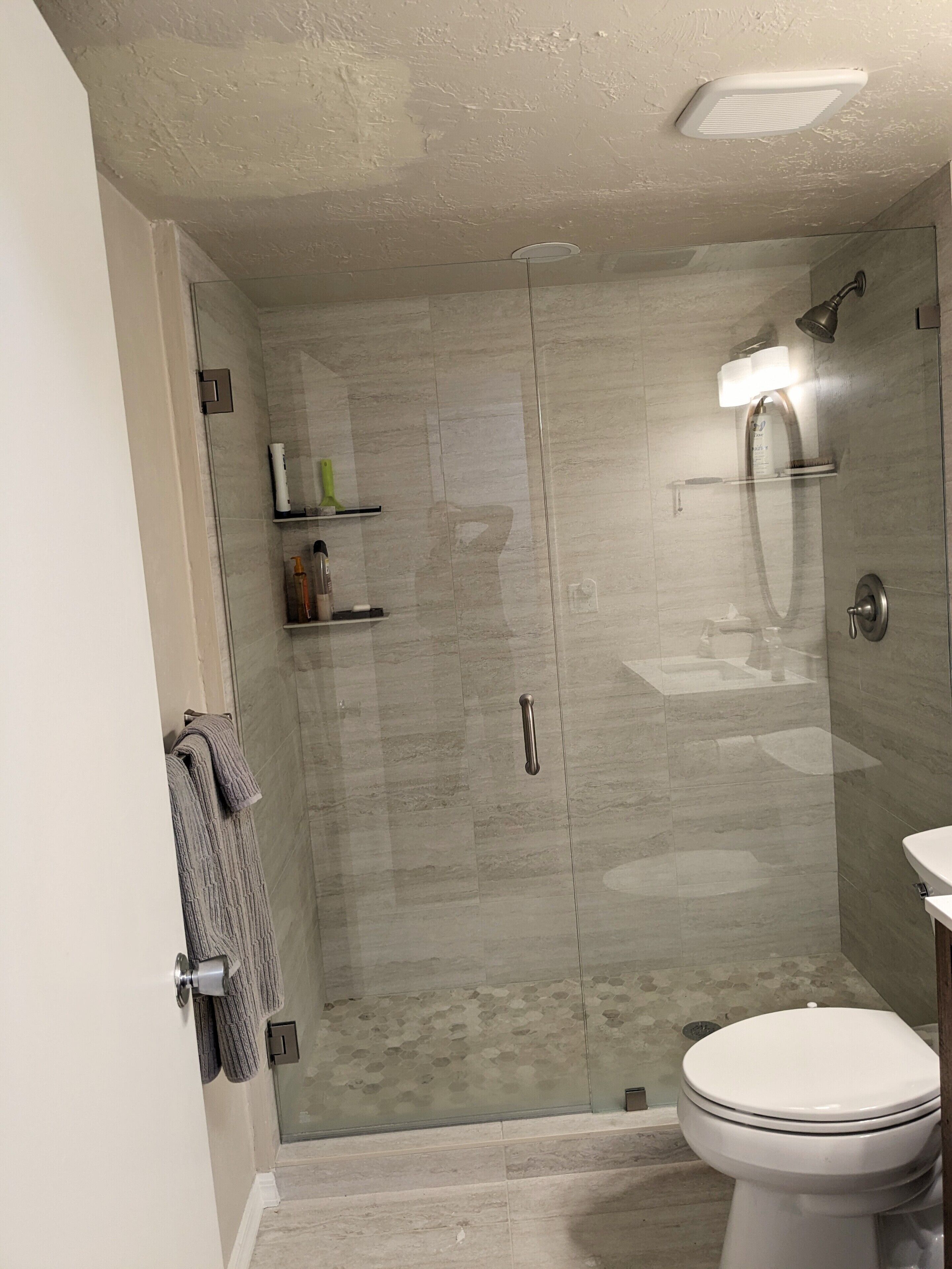 A modern bathroom with a glass-enclosed shower, a toilet, and a sink.