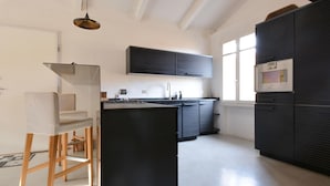 Una cucina moderna con isola centrale, zona pranzo con una sedia e un'ampia finestra che offre luce naturale.
