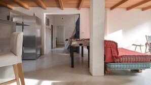 Un'ampia stanza con un letto, un tavolo da calcio, un divano e un tavolo con una coperta rossa.