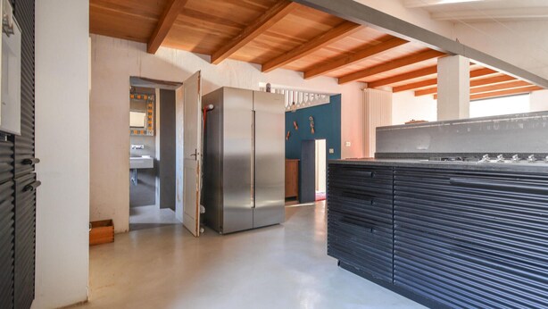 Un'ampia cucina con un'isola centrale grande, elettrodomestici in acciaio inossidabile e soffitto in legno.