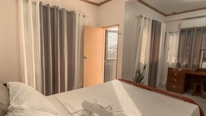 A hotel room with a bed, a wooden dresser, a desk, and a mirror. - La-Rivière: 3-bedroom family-sized house (Lal-lo)
