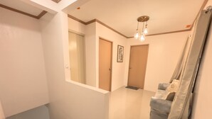A hallway with a staircase, a door, a light fixture, and a couch. - La-Rivière: 3-bedroom family-sized house (Lal-lo)