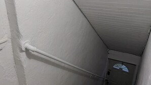 Una escalera estrecha de madera con paredes blancas que conduce a una puerta en la parte superior.