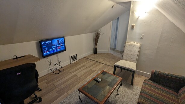 Una sala de estar con televisión, una mesa de centro de madera, una silla y un sofá.