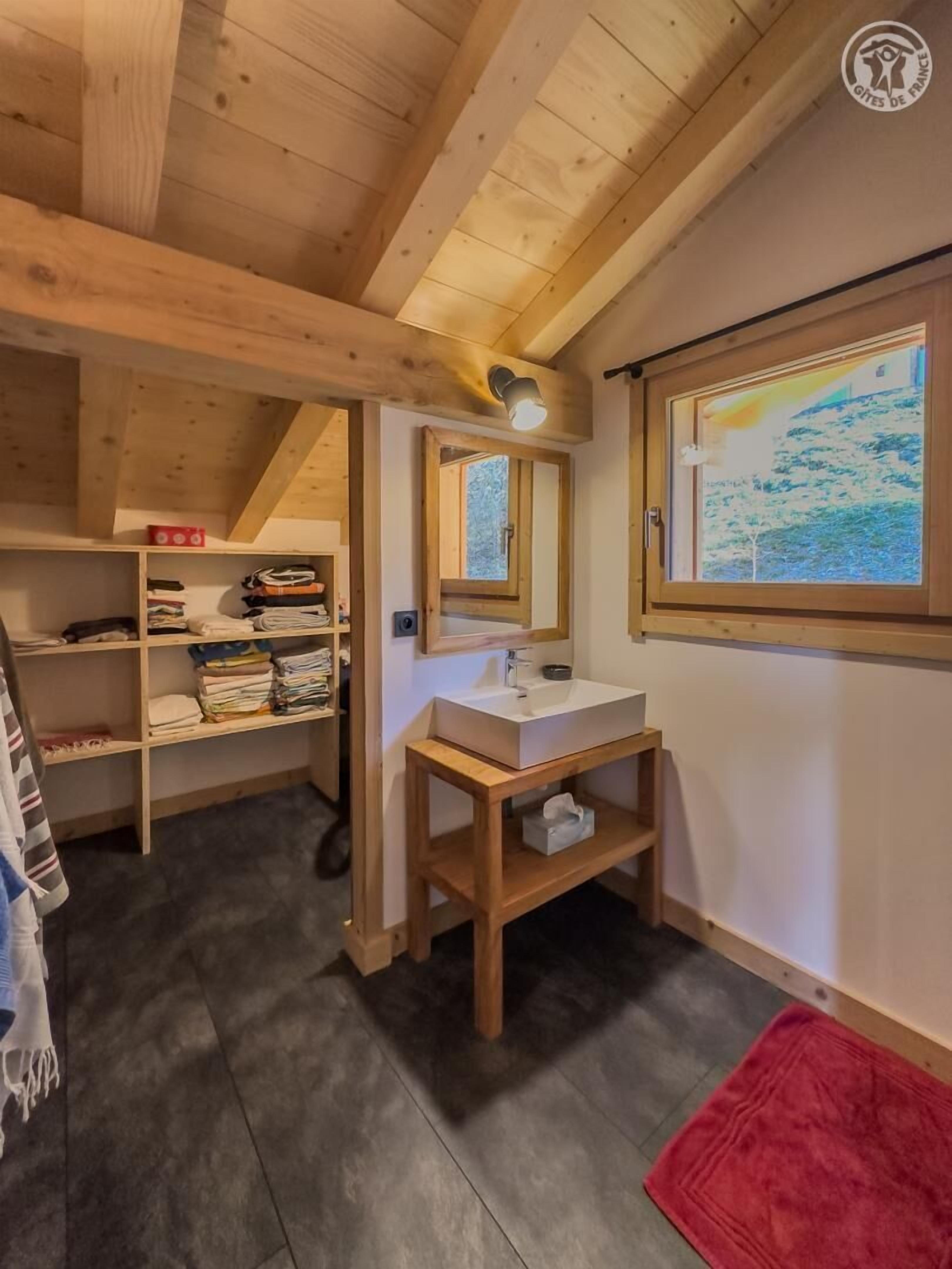 A wooden interior with a built-in shelf, a sink, and a window with a view.