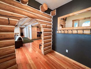 A log cabin interior with a wooden floor, a black wall, and a mirrored section.