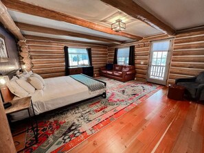 A log cabin bedroom with a bed, a sofa, a rug, and a window.