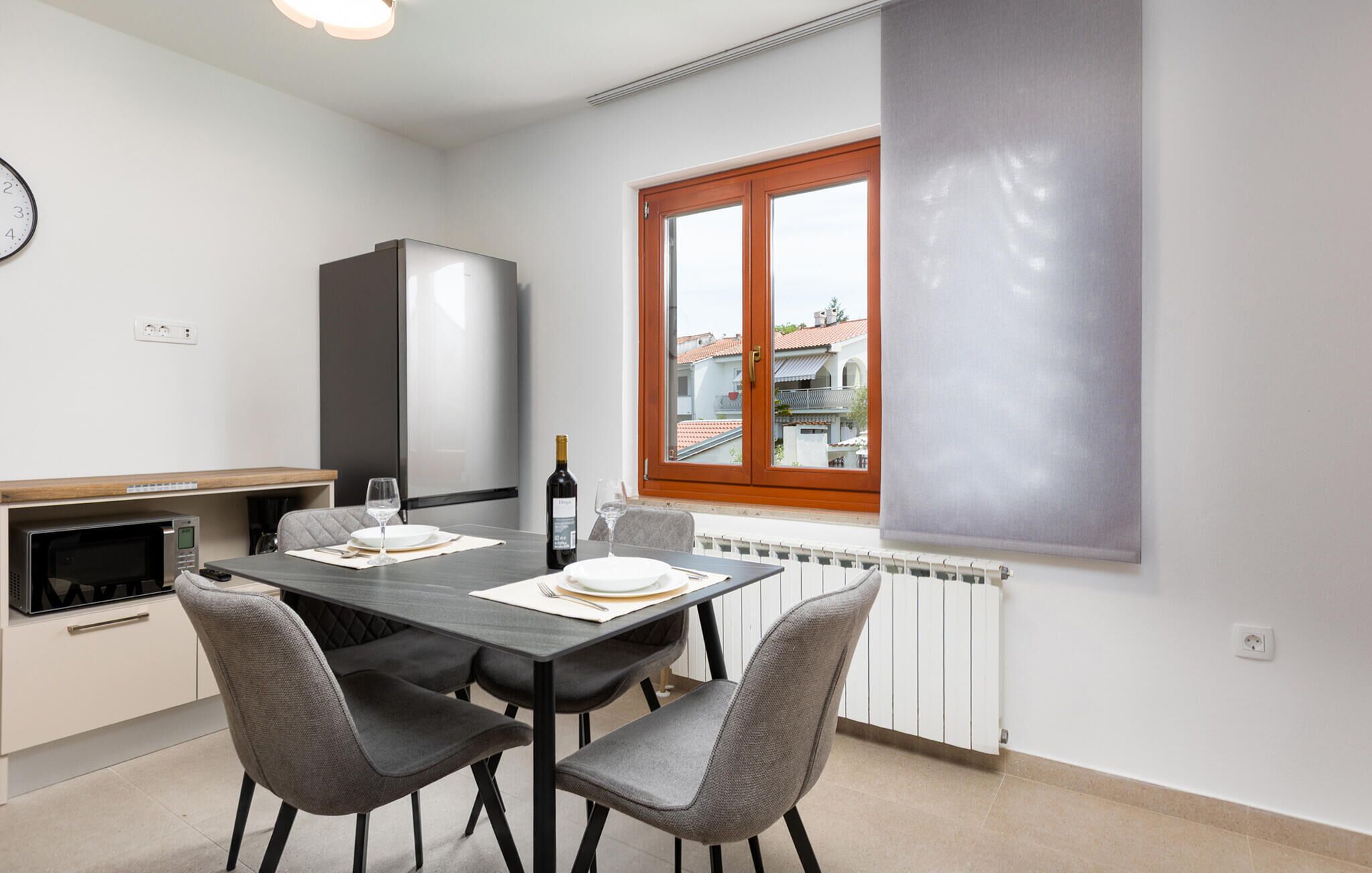 A modern kitchen with a dining table, chairs, a microwave, and a refrigerator.
