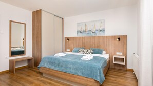 Un dormitorio moderno con una cama de madera, un espejo grande y un cuadro de veleros.