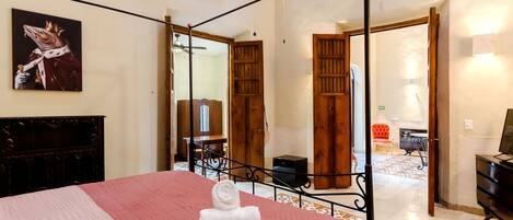 Un dormitorio con cama, ventilador de techo, un cuadro y vista al área de estar.