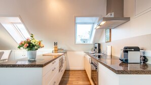 Une cuisine moderne dotée d’un îlot central, d’appareils électroménagers intégrés et d’une lucarne.