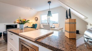 Une cuisine moderne dotée de plans de travail en granit, d’un four encastré et d’un coin repas avec une table et des chaises.
