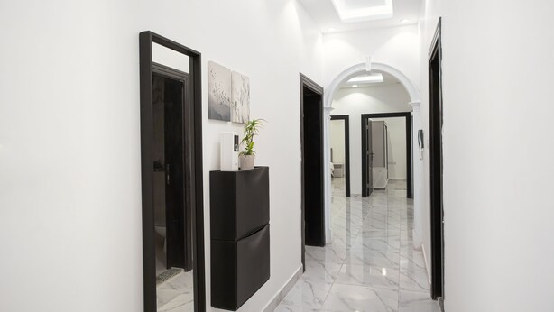 A hallway with a black-framed mirror, a potted plant, and a black cabinet.