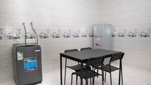 A small, clean room with a table and chairs, a refrigerator, and a water dispenser.