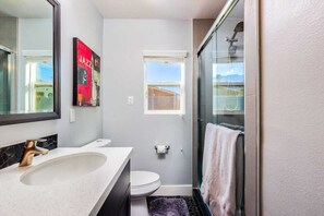 Un bagno moderno con lavandino capiente, toilette e box doccia in vetro.