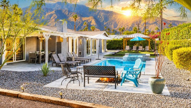 Zona de piscina con sillas de descanso, una pérgola y vistas a las montañas.