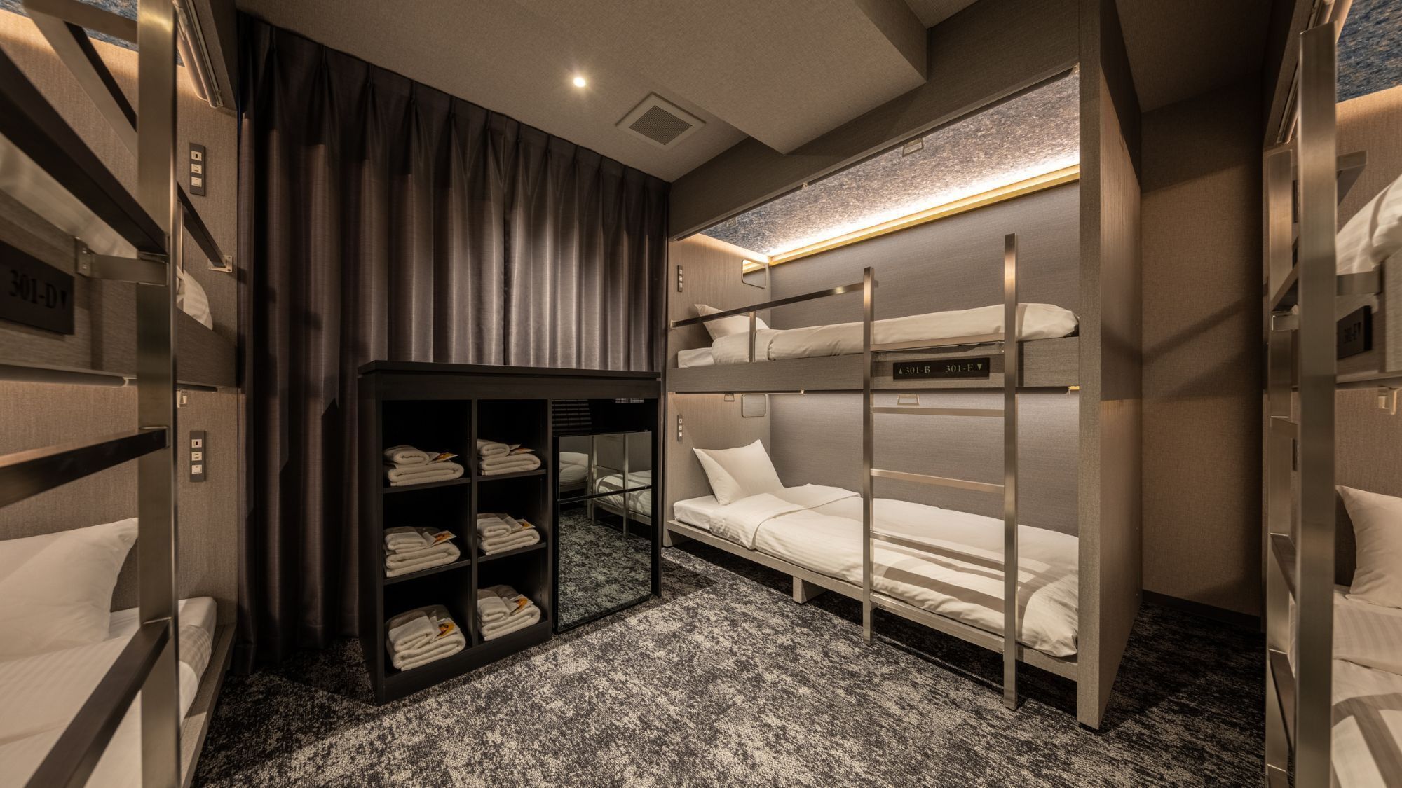 A compact hotel room with bunk beds, a built-in wardrobe, and a carpeted floor.