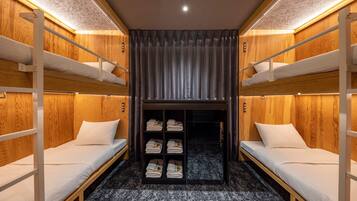 A bunk bed room with wooden walls, a central closet with shelves, and a ceiling light.