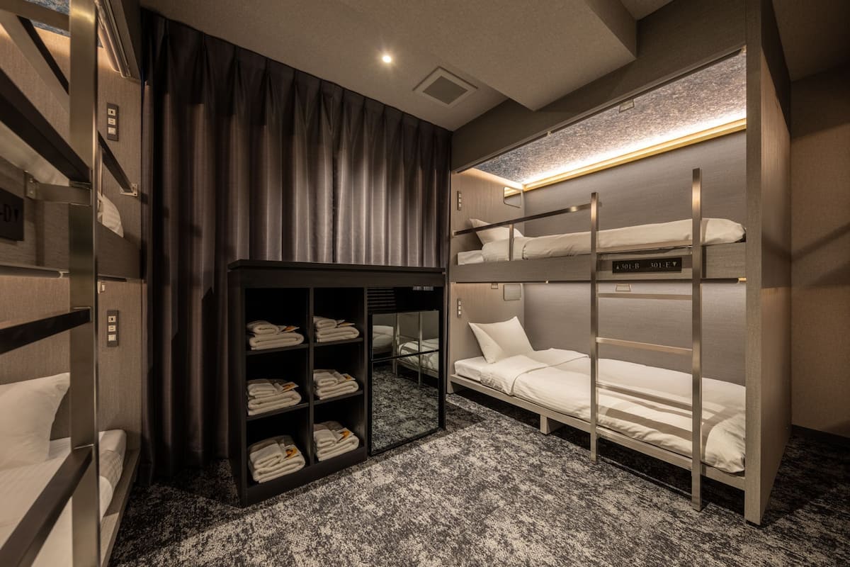 A compact hotel room with bunk beds, a built-in wardrobe, and a carpeted floor.