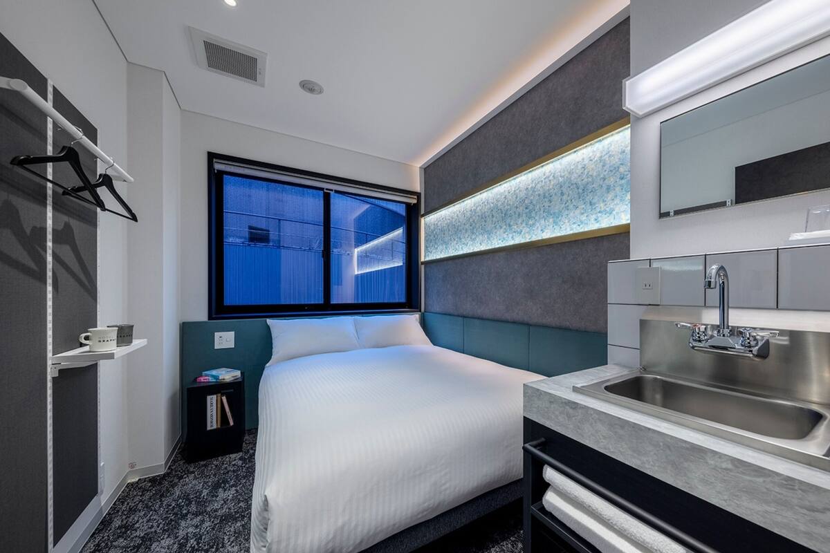 A modern hotel room with a large bed, a built-in sink, and a window with a city view.